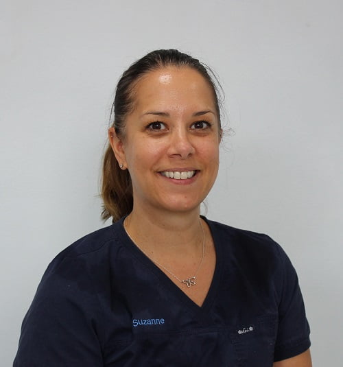 Woman with a ponytail wearing Navy Blue scrubs smiling at the camera